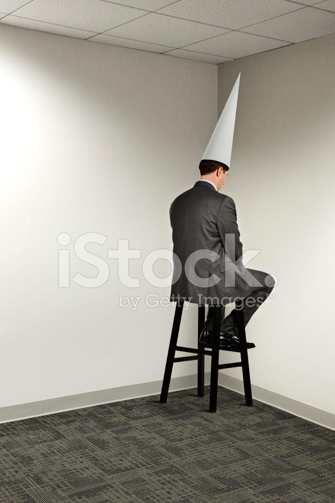 41083032-businessman-sitting-in-office-corner-wearing-dunce-cap.jpg