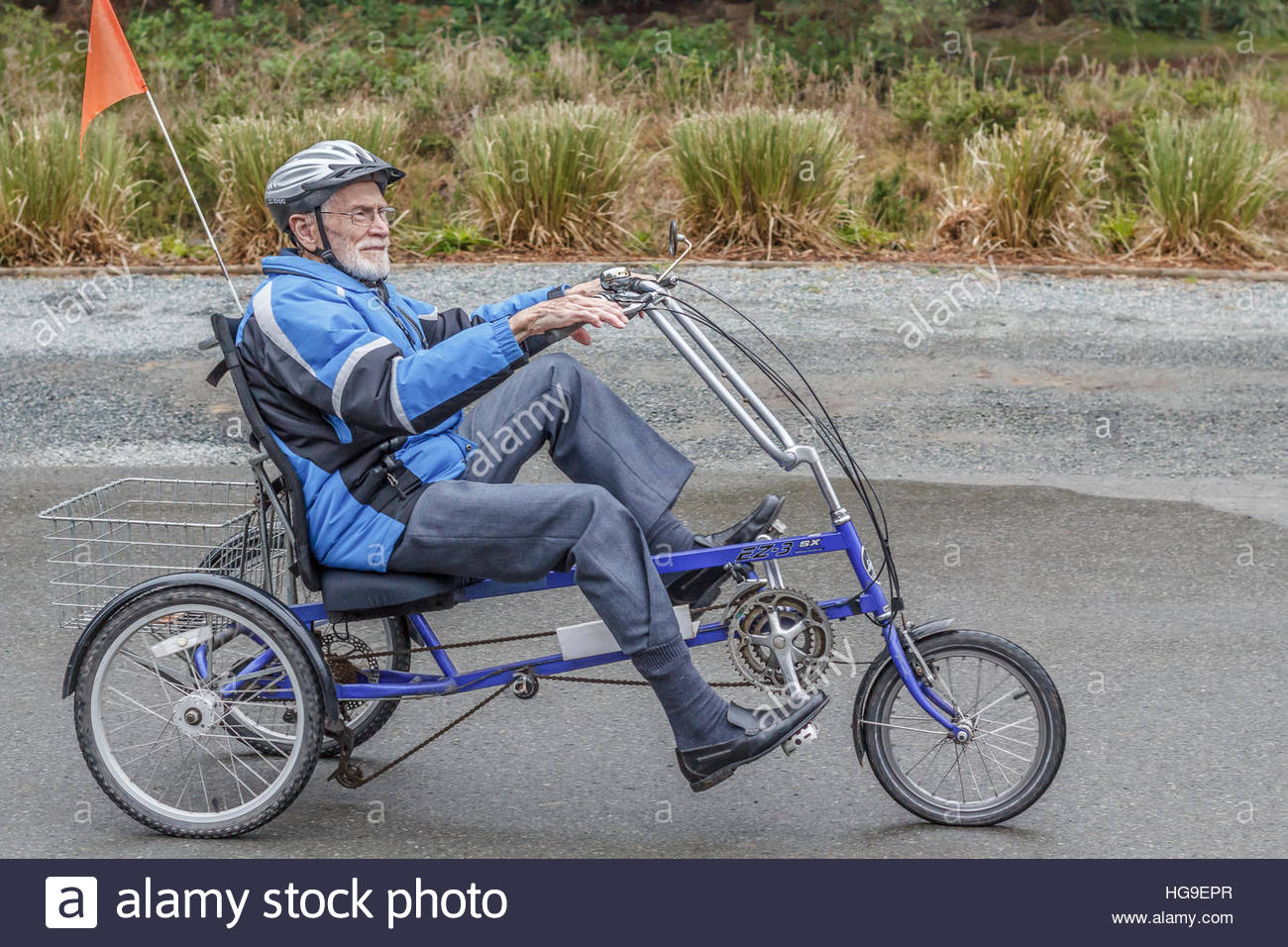 a-smiling-elderly-man-age-94-pedals-a-recumbent-tricycle-along-a-driveway-HG9EPR.jpg